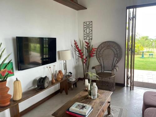 a living room with a tv on a wall at Casa do Mangue-Paraíso na beira do rio Wi-Fi 300 M in Jaguaripe
