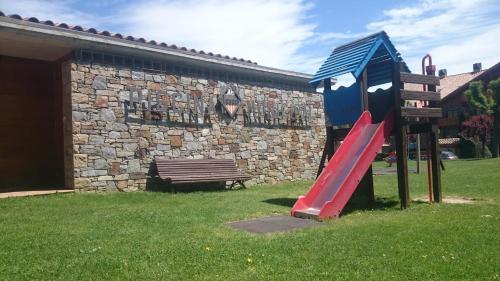 a playground with a red slide and a bench at Hostal l'Escon in Llanars