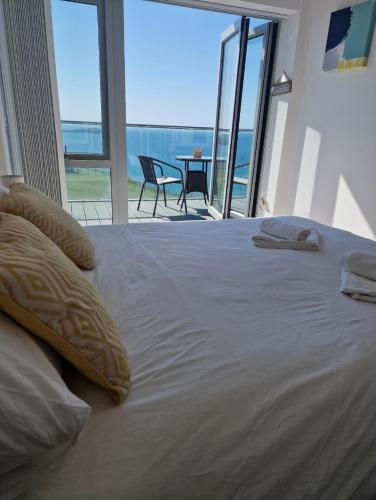 a bedroom with a large bed with a view of the ocean at Sea View Apartment at One Lusty Glaze in Newquay
