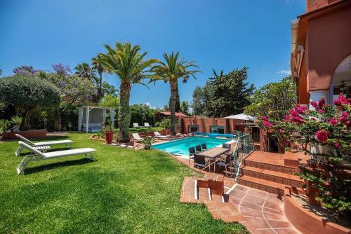 un patio trasero con piscina y palmeras en Villa Tiphareth, en Marbella