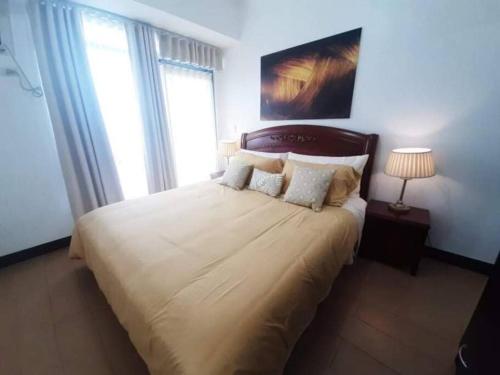 um quarto com uma cama grande com lençóis brancos e almofadas em Cubao Manhattan HEights Unit 6H Tower B, 2BR em Manila