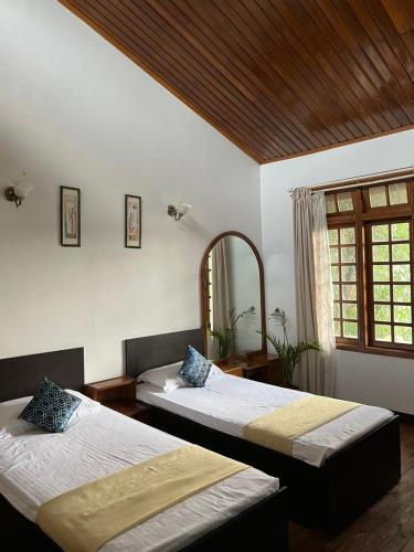a bedroom with two beds and a mirror at BelleVue Home Stay in Shillong
