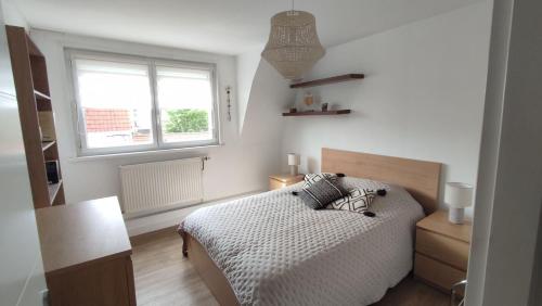 een witte slaapkamer met een bed en een raam bij Malo les bains Appt à 7 minutes de la plage in Duinkerke