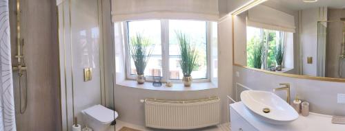 La salle de bains est pourvue d'un lavabo, de toilettes et d'une fenêtre. dans l'établissement Apartament Olchowa Prestige 3, à Ustroń