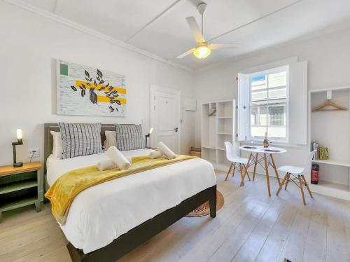 a bedroom with a large bed and a table at Classy and Newly Renovated Studio in Observatory in Cape Town