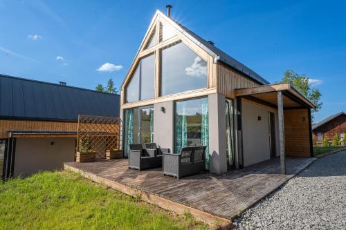a house with a deck with two chairs on it at Stodoły Hołosanka 600-065-145 in Polańczyk