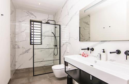 baño blanco con ducha y lavamanos en Ocean Sunset Villa luxury stay max. 14 people, en Dorp Sint Michiel