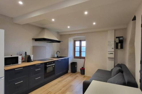 uma cozinha com armários azuis e um sofá num quarto em Maison familiale pour 4 pers. em Ersa