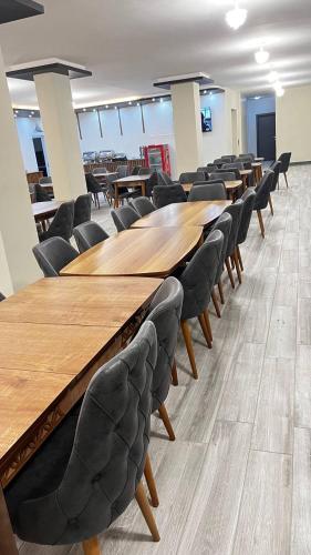 una fila di tavoli e sedie in legno in una stanza di ATLIHAN PLUS HOTEL a Doğubayazıt