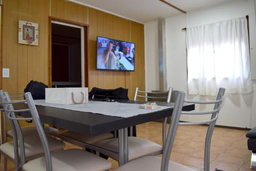 una sala da pranzo con tavolo, sedie e TV di Silvia's house a Ushuaia