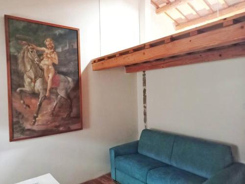 a living room with a blue couch and a painting at CasAlice Room&Breakfast in centro storico in Santarcangelo di Romagna