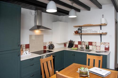 a kitchen with blue cabinets and a wooden table at Relaxing Cottage Escape - Pub - Fire - King Size Bed in Newton Aycliffe