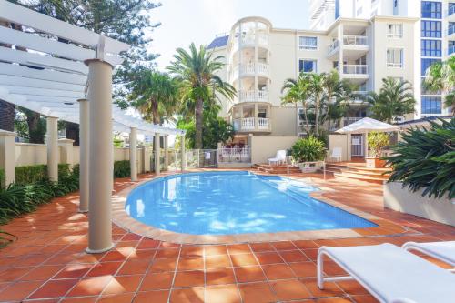 una piscina en medio de un patio con un edificio en La Grande Apartments, en Gold Coast