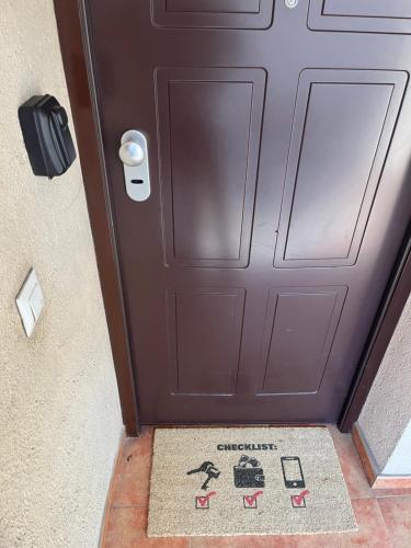 a brown door with a welcome mat in front of it at ALOJAMIENTO LOS DINOSAURIOS in Cuenca