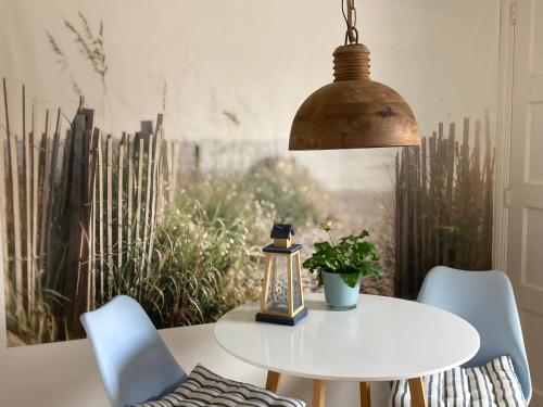 une table blanche avec des chaises et une lampe dans l'établissement Bij Frits, à Zandvoort