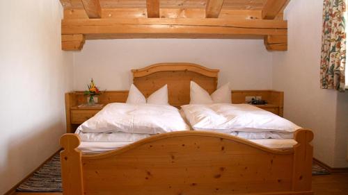 1 dormitorio con cama de madera y almohadas blancas en Lugererlehen en Schönau am Königssee
