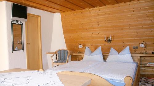 a bedroom with a white bed with a wooden wall at Ferienwohnung Lugererlehen in Schönau am Königssee