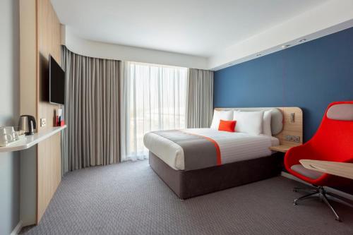 a hotel room with a bed and a red chair at Holiday Inn Express & Suites - Deventer by IHG in Deventer