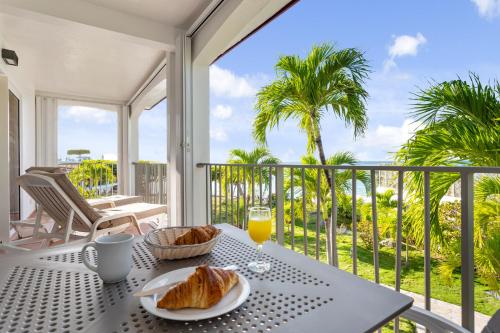 a table with a plate of bread and orange juice on a balcony at Grand Case Beach Club in Grand Case
