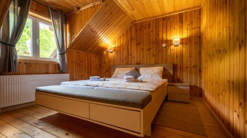a bedroom with a large bed in a wooden room at Apartman DAVID sa unutarnjim bazenom in Brod Moravice