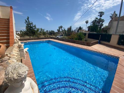 a blue swimming pool with a statue next to a house at River Dreams in Deltebre
