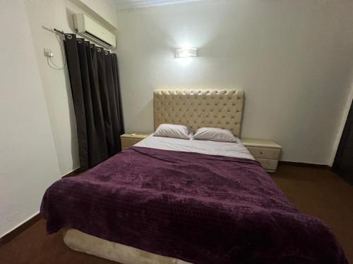 a bedroom with a bed with a purple blanket at Luxury 2BR Family Apt/Wi-Fi / Netflix in Islamabad