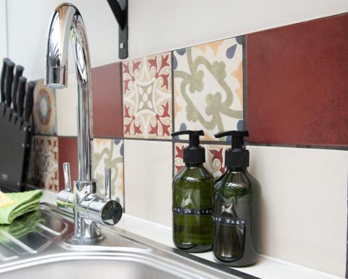 two bottles of detergent sitting on a kitchen sink at Relaxing Cottage Escape - Pub - Fire - King Size Bed in Newton Aycliffe