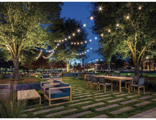 a park with tables and chairs and trees at night at Houston CityPlace Marriott at Springwoods Village in The Woodlands