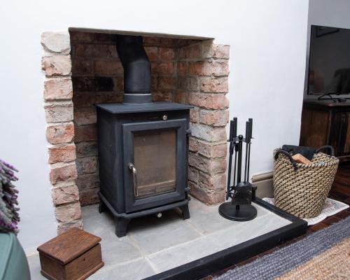 a black wood stove in a living room at Relaxing Cottage Escape - Pub - Fire - King Size Bed in Newton Aycliffe