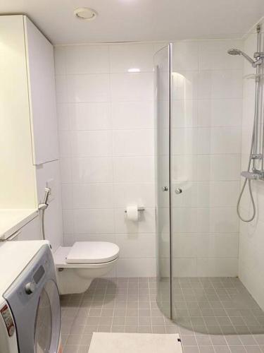 La salle de bains blanche est pourvue d'une douche et de toilettes. dans l'établissement Modern Apartment nearby Kerava, à Kerava