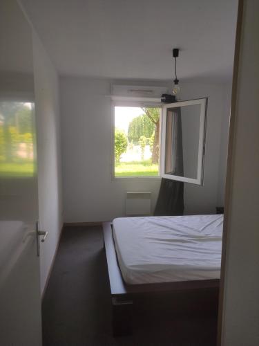 a white bedroom with a bed and a window at Appartement T2 in Limoges