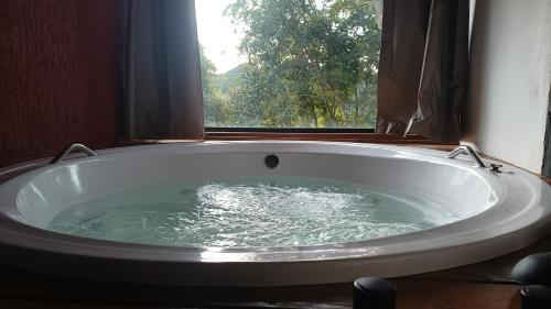 a bath tub in a bathroom with a window at Mountain House Hospedagem in Monte Verde