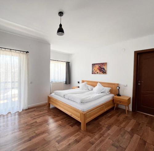 a bedroom with a bed with white walls and wooden floors at Villa NOVA Cozy and Modern -5 min from center in Bran