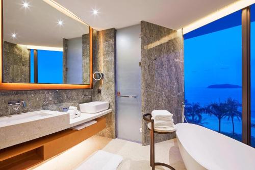 a bathroom with a tub and a sink and a mirror at The Westin Shimei Bay Resort in Wanning