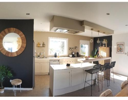 une cuisine avec des armoires blanches et des tabourets de bar dans l'établissement Villa Mon Rêve 12 pers à 500m de la plage, à Bréhal