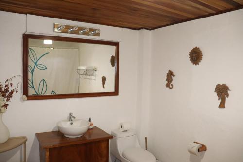 a bathroom with a sink and a toilet and a mirror at Playa Negra Surf Lodge in Playa Negra