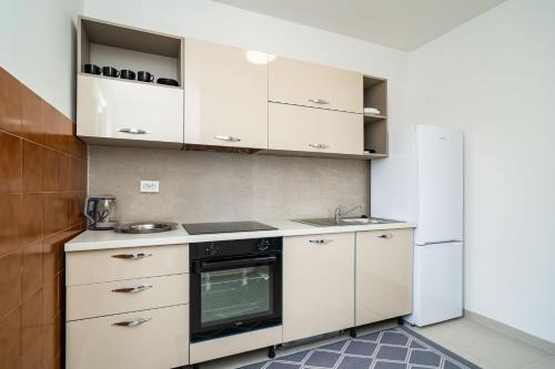 a kitchen with white cabinets and a sink and a refrigerator at Villa Green Sunset in Dubrovnik