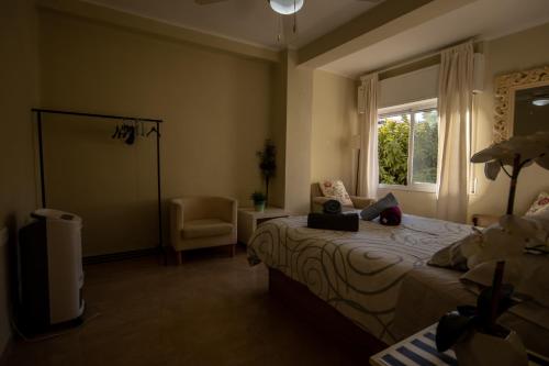 um quarto com uma cama, uma janela e uma cadeira em Apartamento La Traiña em Torre del Mar