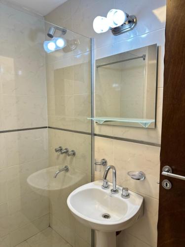 a bathroom with a sink and a shower with a mirror at TempoStay Monoambiente in San Miguel de Tucumán