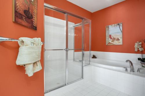 a bathroom with orange walls and a shower with a glass door at Sunset Island Luxury 3BR Unit – Free Linen Package in Ocean City