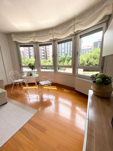 a living room with windows and a table and chairs at Blue house Bermeo in Bermeo