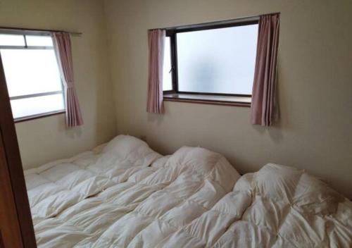 1 cama no hecha en un dormitorio con ventana en Maison Ota Building A Building B - Vacation STAY 14501 en Takamatsu