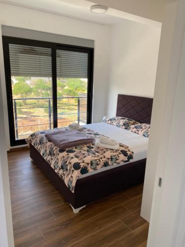 a bedroom with a bed and a large window at Jednosoban Stan Najla in Dobra Voda