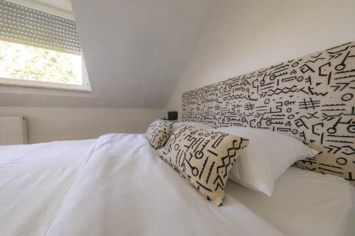 sypialnia z łóżkiem z białą pościelą i poduszkami w obiekcie Neue Wohnung in der Nähe von Trier w mieście Korlingen