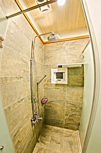 une douche avec une porte vitrée dans une salle de bain dans l'établissement Sasa Nor Lamour B&B, à Eluan