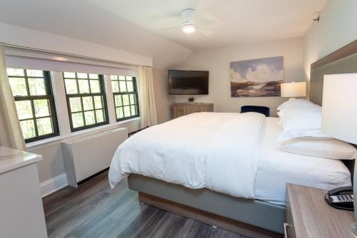 a bedroom with a large white bed and windows at The Glenerin Inn in Mississauga