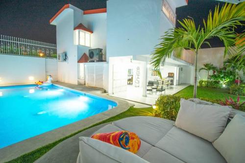 a swimming pool with a white couch next to a house at Casa Nicolasa Alberca y Asador Privados. in Puerto Vallarta