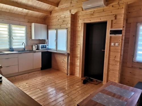 una cocina en una cabaña de madera con una puerta abierta en Puchata Chata - Mazury, en Pozezdrze