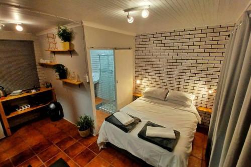 a bedroom with a bed and a brick wall at Woodgate Cottage in Howick