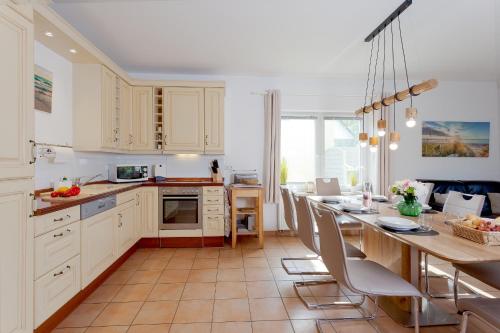 una cocina con armarios blancos y una mesa con sillas. en MEERerholung, en Zinnowitz